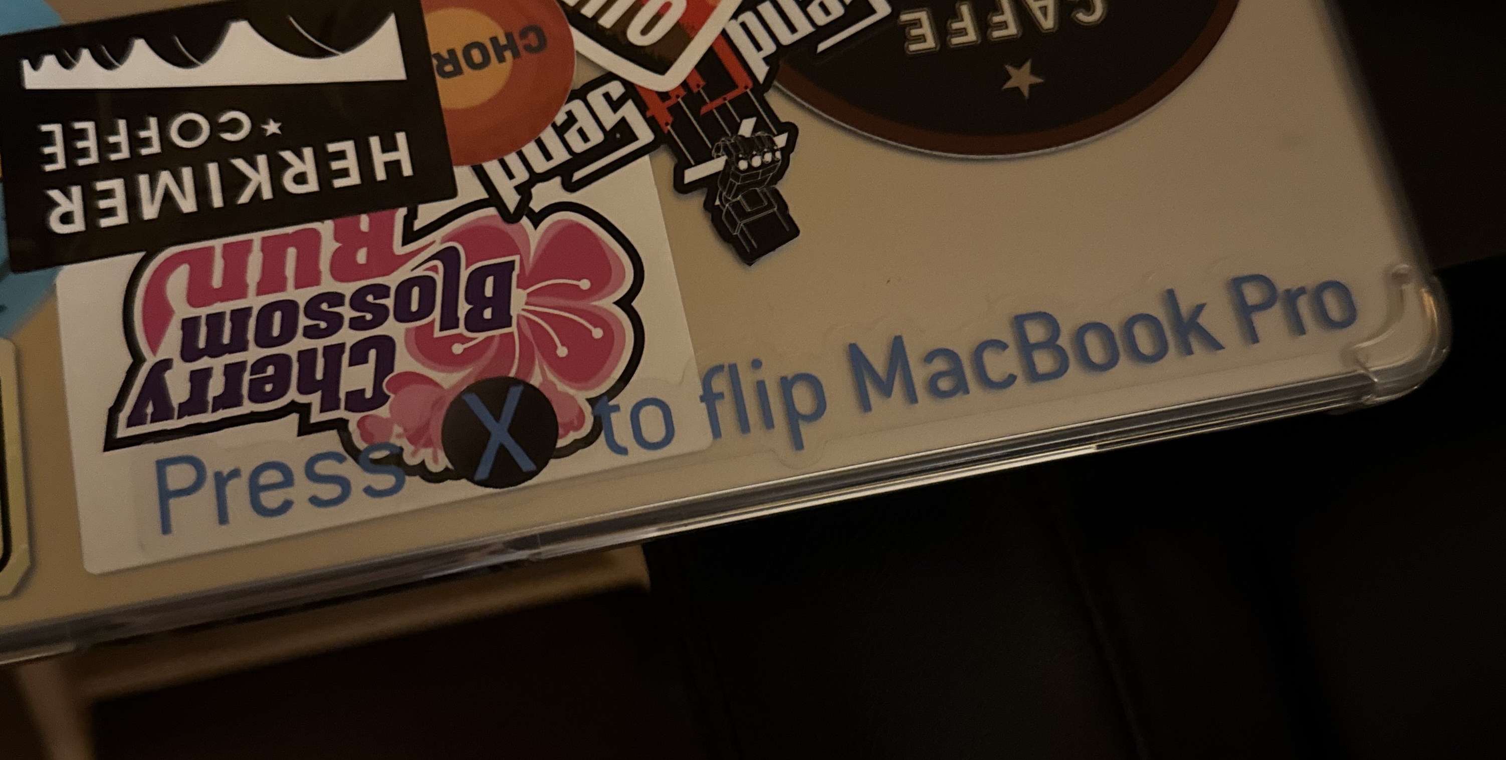 A photo of a corner of a MacBook Pro laptop case, with a sticker saying 'Press X to Flip MacBook Pro' in the style of Halo: Combat Evolved graphics.